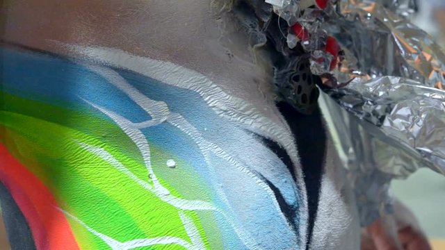 Body art close-up. Creating drawing on the skin of body person with colorful paints and brush. Artistic creation creativity