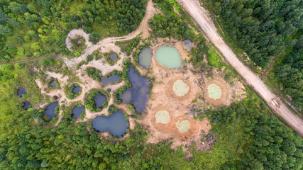 Holes on ground from powerful explosions. Bomb craters in the forest. Disposal of explosives. Top view aerial photo from flying drone. © Artem Zarubin
