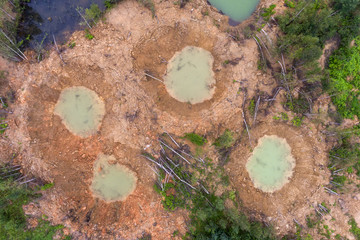 Holes on ground from powerful explosions. Bomb craters in the forest. Disposal of explosives. Top view aerial photo from flying drone. © Artem Zarubin