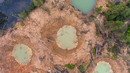 Holes on ground from powerful explosions. Bomb craters in the forest. Disposal of explosives. Top view aerial photo from flying drone.