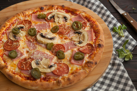 pizza, fresh pizza with mozzarella, tomatoes, pepporoni and cheese. Italian pizzeria. Fresh pizza on the kitchen table