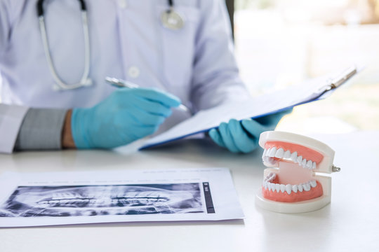Male doctor or dentist working with report and patient tooth x-ray film, model and equipment used in the treatment and analysis teeth disease of dental and dentistry at workplace