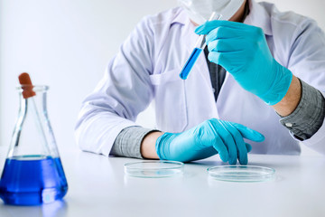 Biochemistry laboratory research, Scientist or medical in lab coat holding test tube with reagent with drop of color liquid over glass equipment working at the laboratory