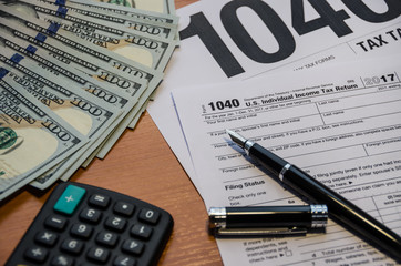 Tax form 1040, dollars, pen and calculator