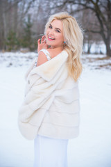 Holidays days, Christmas winter time. Woman in elegant dress and fur coat outdoor. Girl in fashionable clothes, ladies fashion concept, posing on the street in snowy weather 