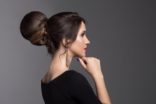 Fashion woman on a dark background. Beautiful hairstyle and fitting black dress. Hairstyle bundle