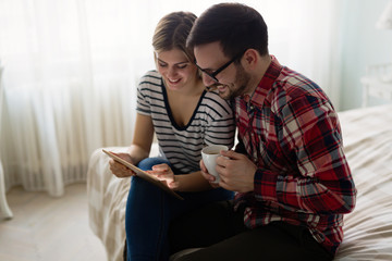 Obraz premium Young attractive couple using tablet in bedroom