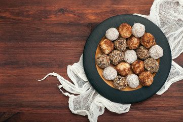 Useful fitness sweets from dried fruits, nuts and seeds, without sugar on a plate on the brown...