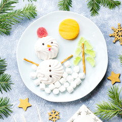 Christmas Snowman made of marshmallow and fruit jelly on a plate with fir branches and decorations. Top view, copy space