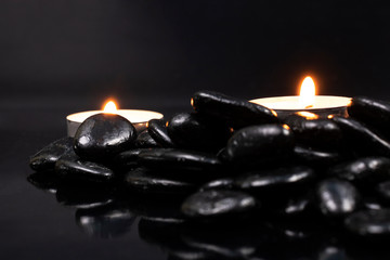 candles among black stones with reflection