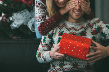 Young woman surprise beloved man with Christmas present