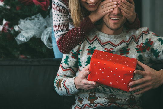 Young woman surprise beloved man with Christmas present