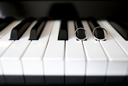 Teclas de piano blancas y negras con dos anillos de unión tocando la música