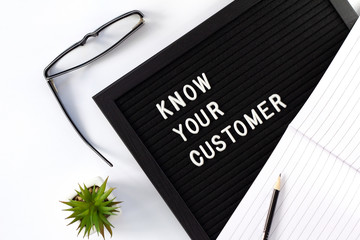 Know Your Customer - business concept, white text message on black board with green plant