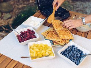 Preparation of homemade waffles in waffle irons outdoors in the garden © bubutu