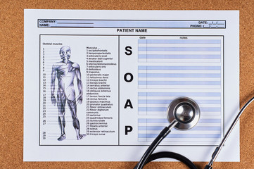 Patient SOAP note sheet, stethoscope on corkwood background. Flat lay.