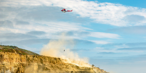 Fototapeta na wymiar Helicopter in flight on cloudy sky above a cliff