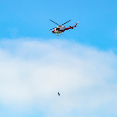 Helicopter with person hanging by rope in La Jolla