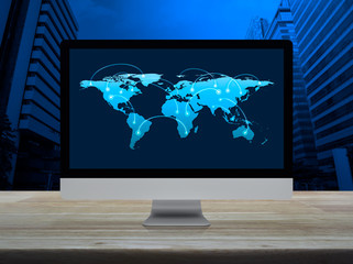 Connection line with global world map on desktop computer monitor screen on wooden table over modern city tower and skyscraper, Communication online concept, Elements of this image furnished by NASA