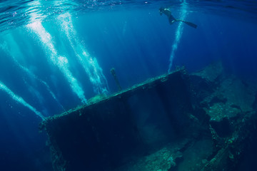 Freediver man swim in sea near shipwreck in Bali