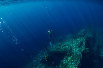 Fototapeta na wymiar Free diver man dive underwater at shipwreck in Bali