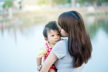 mom is holding in her arms her little boy and kissing him