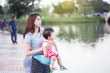 Young mother with her toddler child in a baby carrier