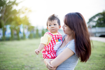 Portrait of a crying little boy who is being held by her mother