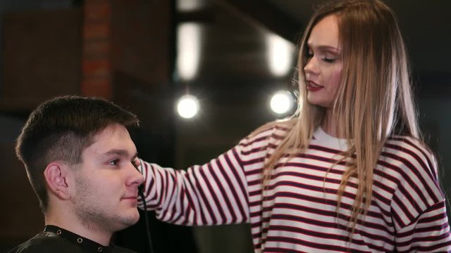 Hairdresser cutting male hair with electric shaver in beauty school. Woman haircutter making male haircut with hair clipper in barbershop close up