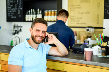 Fototapeta premium Coffee take away option for busy people. Man with smartphone order coffee. Coffee break concept. Lets meet in cafe. Man mobile conversation cafe barista background. Drink coffee while waiting