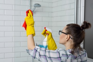 House cleaning. Woman cleaning the bathroom, female in casual clothes with detergent and washcloth at home in the bathroom