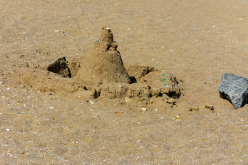Sandy castle built by children with wet sand on the beach. Castles on the sand. Fun in the sand on the beach on a sunny day. Concept of summer vacation and travel.