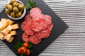 delicious sliced salami on a stone plate wooden background