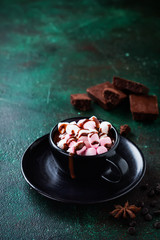 Hot chocolate with anise and nuts in black ceramic cup on old dark green concrete background. Selective focus.