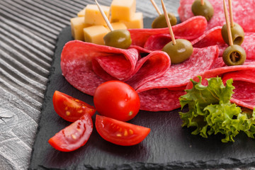 delicious sliced salami on a stone plate wooden background