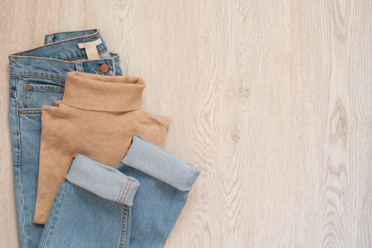 Women Fashion Clothes On Wooden Background. Flat Lay Of Female Styled Look. Polo Blouse And Jeans. Top View. Shopping Concept. Fashion Set Outfits. Copy Space