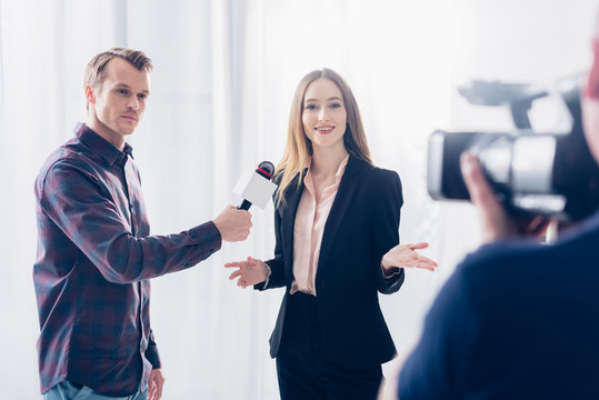 beautiful businesswoman in suit giving interview to journalist and gesturing in office