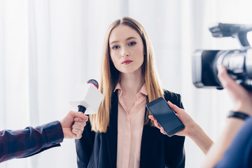 attractive businesswoman giving interview to journalists in office