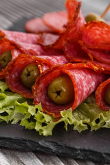 delicious sliced salami on a stone plate wooden background