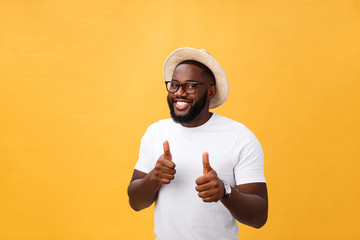 Image of cheerful young african man standing and posing over yellow background with thumbs up. Looking at camera