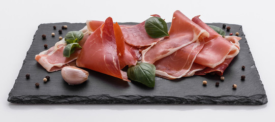 Italian prosciutto crudo or spanish jamon on a stone plate white background