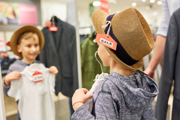 Junge beim Hut kaufen vor dem Spiegel