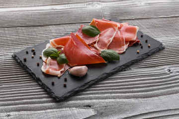 Italian prosciutto crudo or spanish jamon on a stone plate wooden background