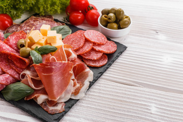 Cold smoked meat plate on a rustic wooden background