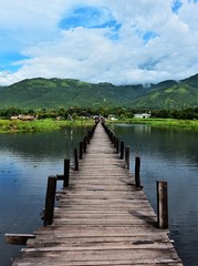 Pier into nature. A wooden bridge at Inle Lake surrounded by water leading toward the horizon. 