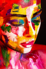 face of young girl painted with colorful makeup and body art