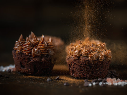Chocolate cake muffin with cocoa creme on dark moody background. Homemade recipe cooking and baking.