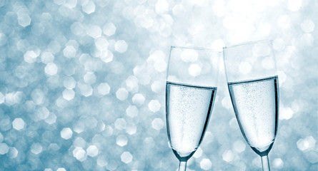 Champagne for the new year on blue winter background with festive bokeh with space for text