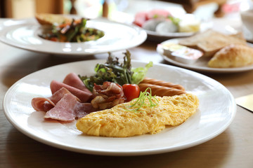 Breakfast set Omelette with sausage bacon and salad on wood background