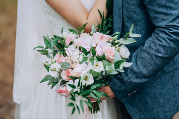 Obraz na płótnie Canvas bride holding bouquet of flowers in rustic style, wedding bouquet Groom hugs bride